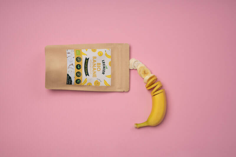 gefriergetrocknete Banane und frische Banane vor rosa Hintergrund